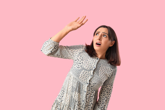 Scared young woman on pink background