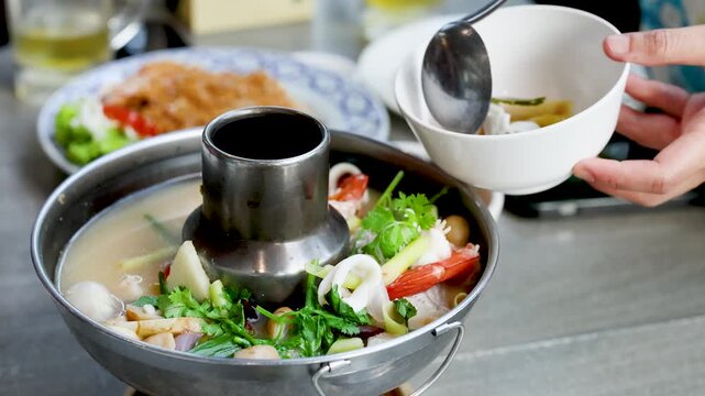 Serving Spicy Thai Tom Yum Seafood Hot Pot in Bangkok Restaurant