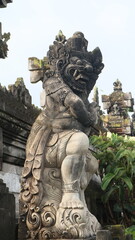 Obraz premium Giant statues, also known as bhuta kala, Dwarapala, gatekeeper statues carrying cups, torches, and weapons, with frightening faces. They wear Balinese poleng cloth. Photo raw, no edit.