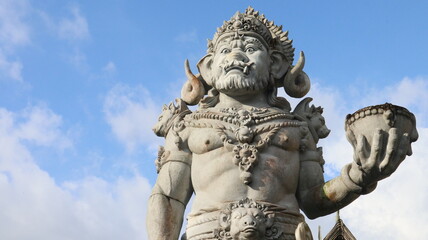 Obraz premium Giant statues, also known as bhuta kala, Dwarapala, gatekeeper statues carrying cups, torches, and weapons, with frightening faces. They wear Balinese poleng cloth. Photo raw, no edit.