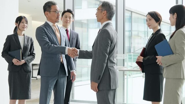 オフィスで握手するビジネスパーソンのグループ