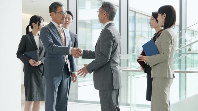オフィスで握手するビジネスパーソンのグループ