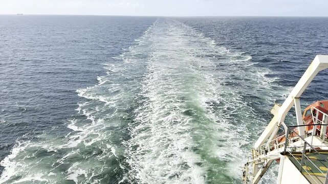 big cargo vessel passing at Ocean. ship propeller burn the water and make keel jet till horizon. 