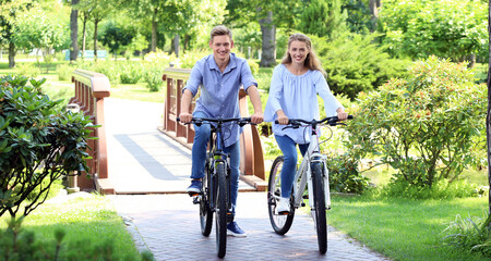 Obraz premium Young couple riding bicycles in park