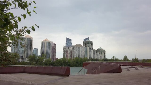 Calgary downtown skyline and bow river from a park in prince island with modern apartment buildings under cloudy sky.
