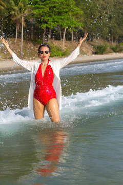 Woman in red swimsuit enjoy with wave on beach