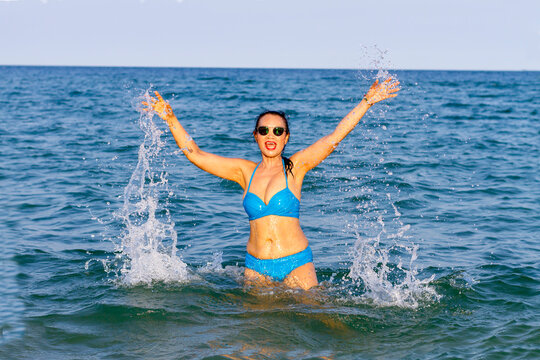 Woman in blue bikini happy with wave