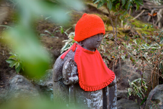 Stone Jizo statue with red bib and knitted hat in Japan