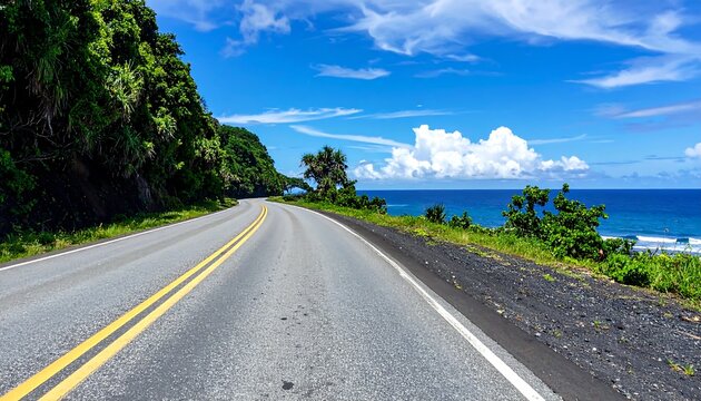 Coastal road stretches toward the horizon, flanked by lush greenery, leading to the bright blue ocean under a cloudy sky