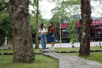 Obraz premium Young women students walking talking on university campus path