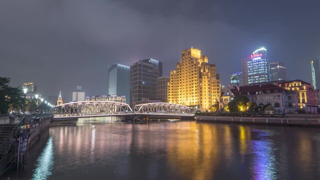 Night riverfront skyline with illuminated bridge in Shanghai, China