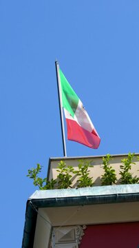 Italian Flag Waving on Rooftop Garden Against Clear Blue Sky