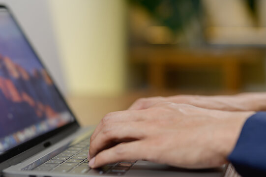 Close-Up of Hands Typing on a Laptop Keyboard in a Workspace
