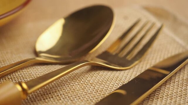 Gold fork and spoon on a table setting with a napkin