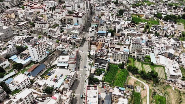 Aerial view of dense urban neighborhood with apartment buildings and farmland plots