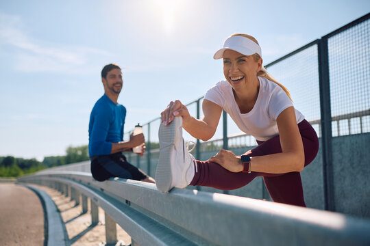 Happy athletic woman warming up for a run outdoors.