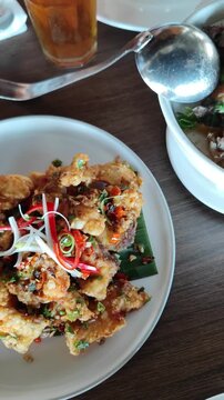 Smooth moving camera shot featuring several delicious Asian dishes served on a dining table, including stir-fried vegetables, crispy seafood, rice, and soup. Warm restaurant atmosphere with cinematic 