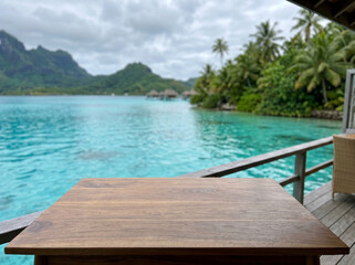 Fototapeta premium Wooden table overlooking turquoise lagoon and overwater bungalows in Bora Bora
