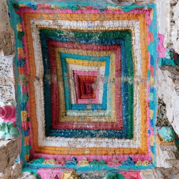 Intricate polychrome painted ceiling features colorful concentric geometric patterns on aged stone for architectural heritage study, cultural tourism and art history