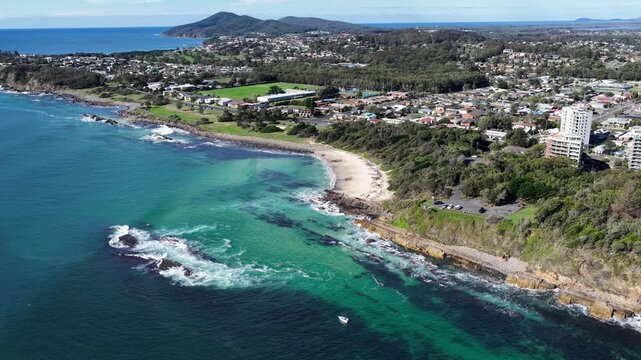 Aerial video panning around 2nd Head Lookout and Pebbly Beach in Forster, NSW, Australia. The sweeping movement reveals the rugged coastline, sandy beach, coastal vegetation and ocean