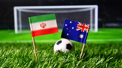 Small flags of iran and australia on a soccer field with a ball in the background, representing a football match between the two countries © Photo Agency