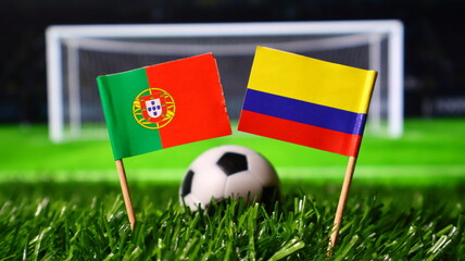 Flags of portugal and colombia on a soccer field with a ball in the background, representing a football match between the two countries © Photo Agency