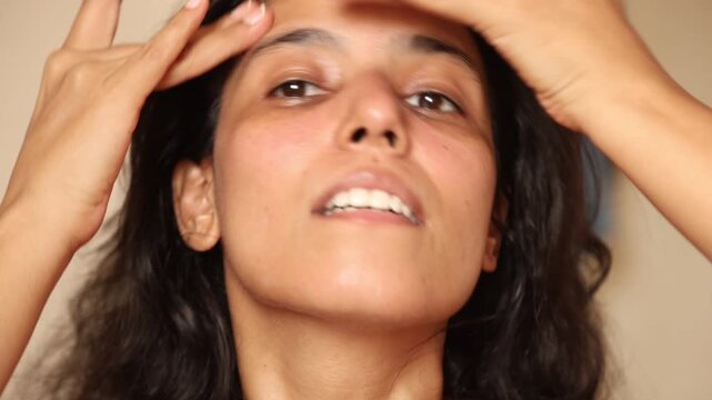 An Indian woman washing her face and doing her skin care routine in her 30s