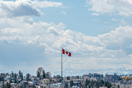 Canadian flag flying over Calgary with mountains in background