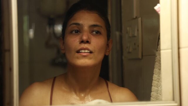 An Indian woman washing her face and doing her skin care routine in her 30s