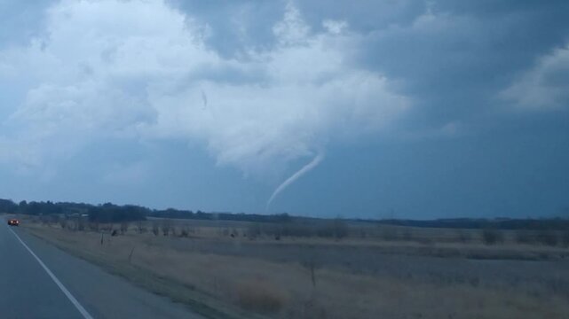 A rope tornado hangs beneath a storm cloud in this storm chaser dashcam footage.