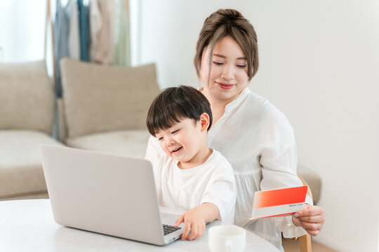A single mother is looking at her computer and bankbook while holding her child.
