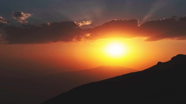 Timelapse cinematic golden sunset mountains sun rays piercing clouds dramatic sky silhouette nature landscape spiritual hope inspiration light rays wilderness horizon outdoor vista. Gods suns eye