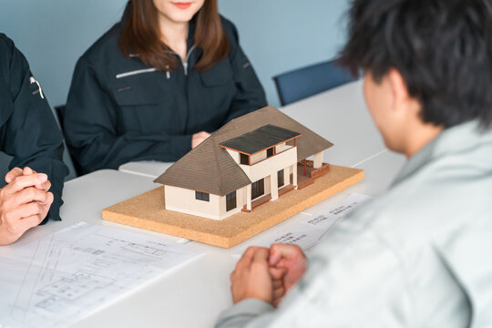Male and female businessmen in work clothes from the construction and building industries use residential models for business negotiations, explanations, and presentations.