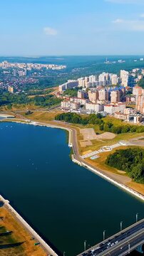 Vertical video. Cheboksary, Russia. Drone footage over Cheboksary Bay and the Volga River, with the Mother Patroness Monument rising above the waterfront cityscape.. Drone footage. Rich colors