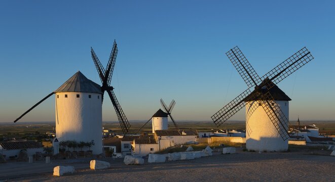 Three white windmills in a sunny landscape at sunrise in Spain, Campo de Criptana, province of Ciudad Real, Castilla-La Mancha, Route of Don Quixote, Spain