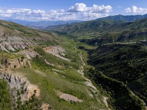 Wide view over a valley with green slopes, surrounding mountains and clouds in the sky, aerial view, landscape near Aghnjadzor, Vardenis Mountains, Vayots Dzor Province, Vayots Dzor, Silk Road, Armenia