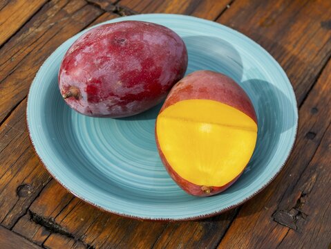 Mangos (Mangifera indica) on plate, yellow flesh, red skin, Osteen variety