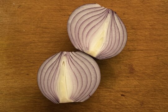 Sliced, halved red onion lies on wooden board