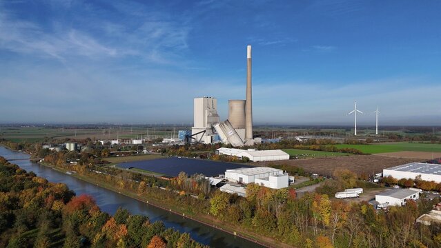 Industrial landscape with power plant and wind turbines, surrounded by autumn trees along a canal, blasting of the ash silos, Mehrum coal-fired power plant, Peine district, Lower Saxony, Germany