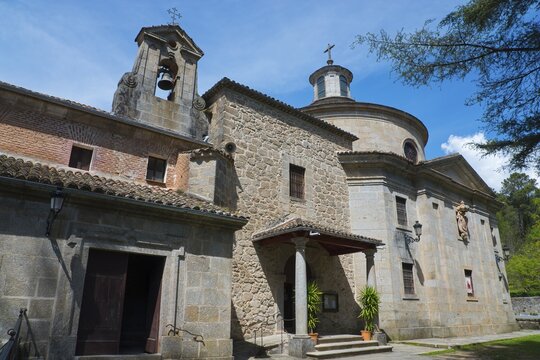 Stone church with bell tower and cross, surrounded by nature and under a blue sky, Santuario de San Pedro de Alc&aacute;ntara, Monastery, Sanctuary of San Pedro de Alcantara, Arenas de San Pedro, &Aacute;vila, Avila, Castilla y Le&oacute;n, Leon, Spain