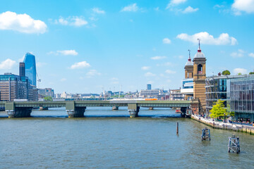 Obraz premium London Bridge spans River Thames modern glass skyscrapers historic brick towers blue sky cityscape, British capital urban waterfront architecture, England UK landmark skyline, United Kingdom tourism
