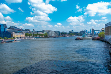 Fototapeta premium London Bridge spans River Thames modern glass skyscrapers historic brick towers blue sky cityscape, British capital urban waterfront architecture, England UK landmark skyline, United Kingdom tourism