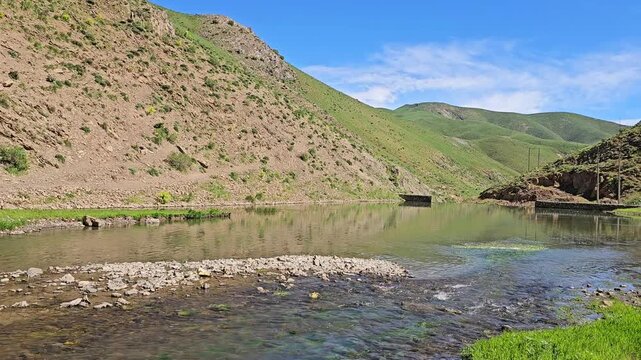 Tranquil spring river flowing through a green valley with clear reflections, rocky hillsides, and vibrant vegetation under a bright blue sky.
📍 Marivan, Kurdisatn, Iran 