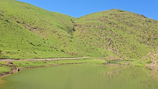 Calm spring lake surrounded by green hills, reflecting the landscape and blue sky, creating a peaceful and natural mountain scene.
📍 Marivan, Kurdistan, Iran 