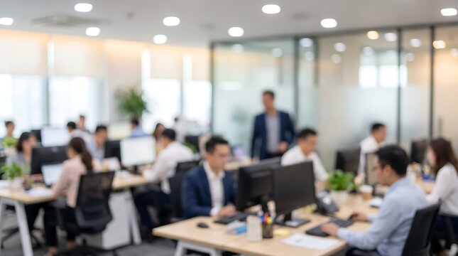 Group of business professionals working in a blurred office environment with employees at desks and computer workstations during a busy workday in a corporate setting