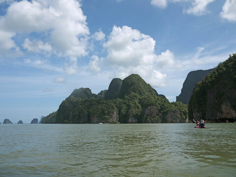 Tourists in an inflatable kayak paddling toward towering limestone Koh Panak karst island in Thailand