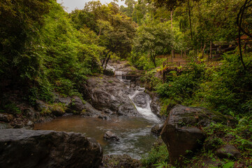 Fototapeta premium A waterfall with rocks and lush green trees in the forest.