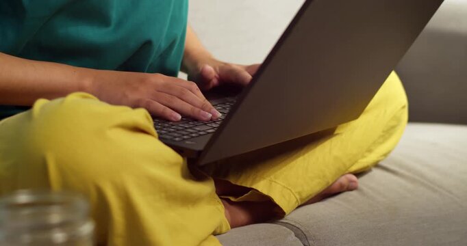 A person types a laptop while relaxing at home capturing essence of remote work comfort.