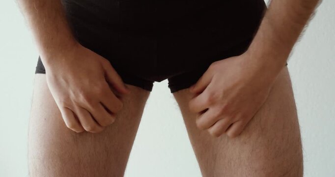 man scratching his inner thigh and groin area, representing intimate itching, skin irritation, discomfort, hygiene issues, heat rash, fungal infection risk, and personal health problems.