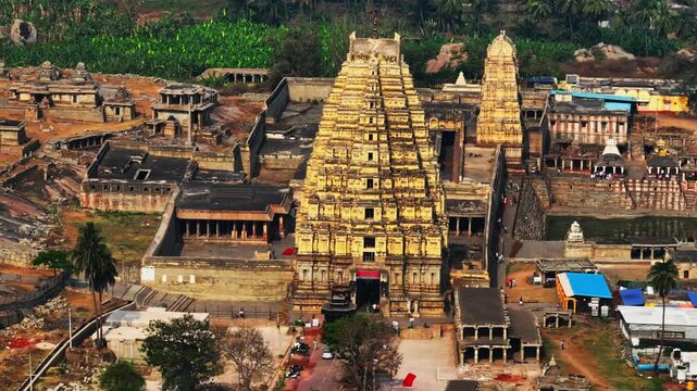 Close up shot of Virupaksha Temple Gopuram with Manmatha Tank, 100 pillared hall and Temples on Hemakuta Hill at hampi, Vijayanagara, karnataka, india. day time, push back shot, drone shot, 4k.